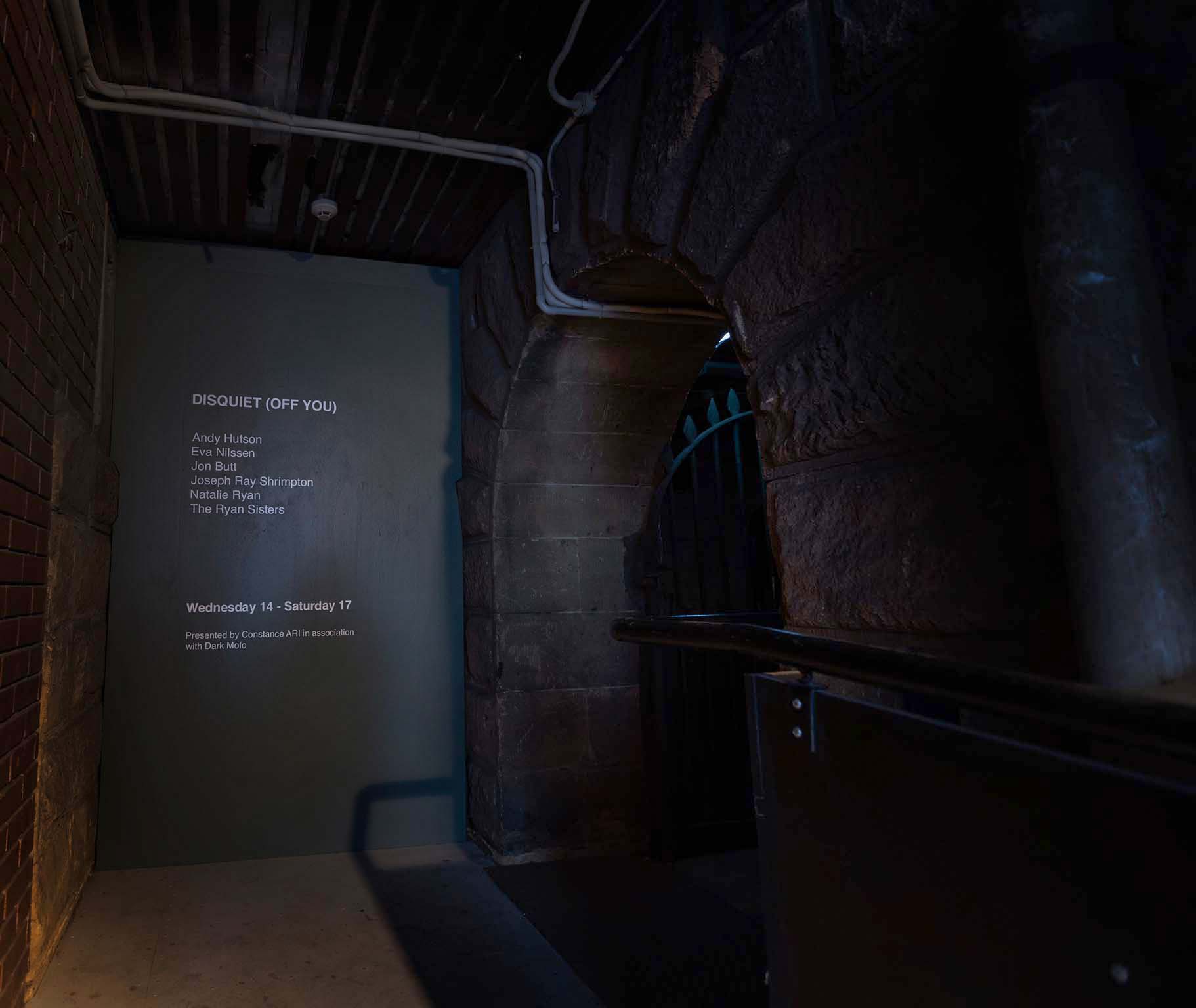 Entrance wall text in a dark underground passage for Disquiet Off You