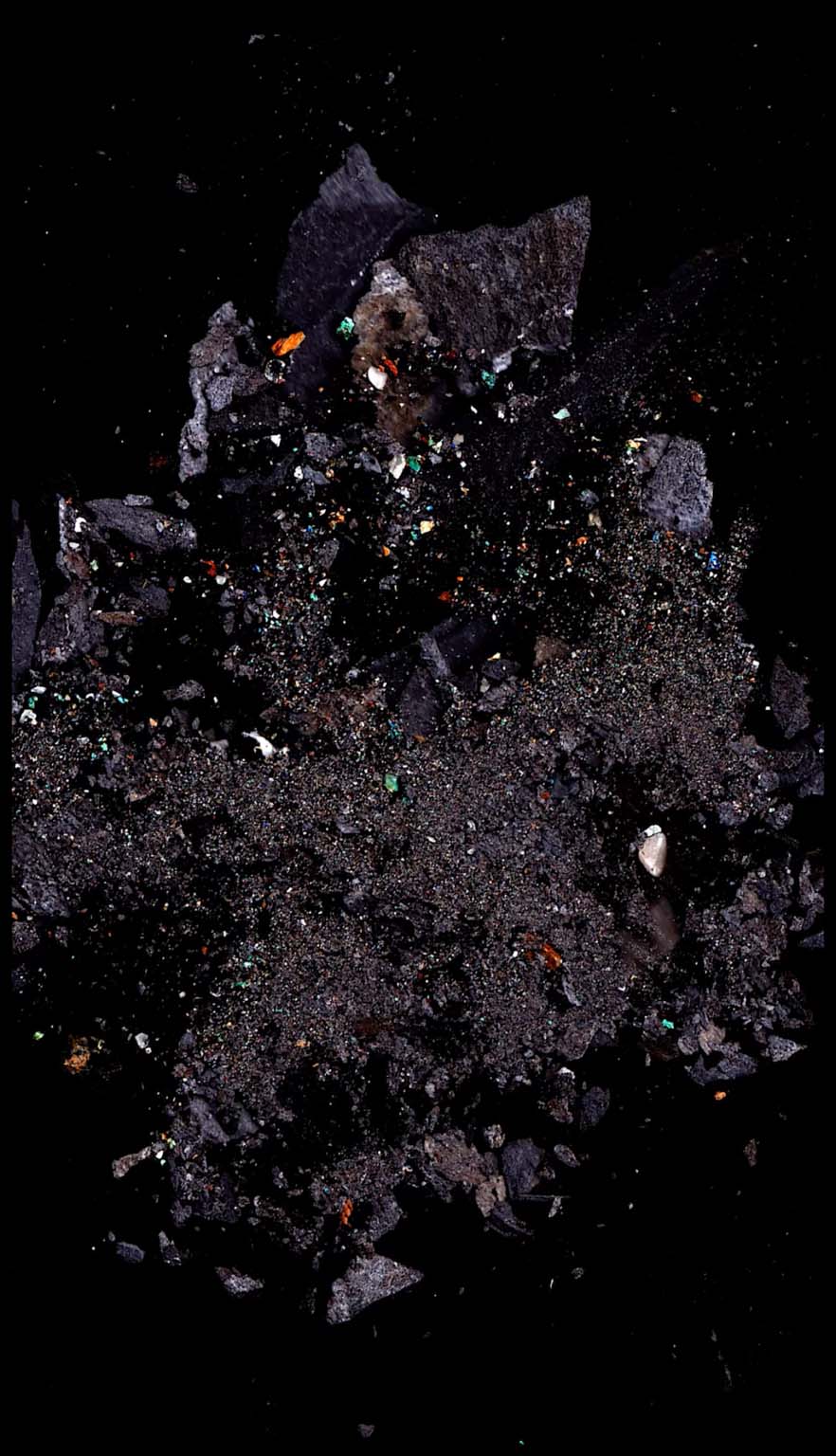 Dark mineral fragments with small coloured shards against black