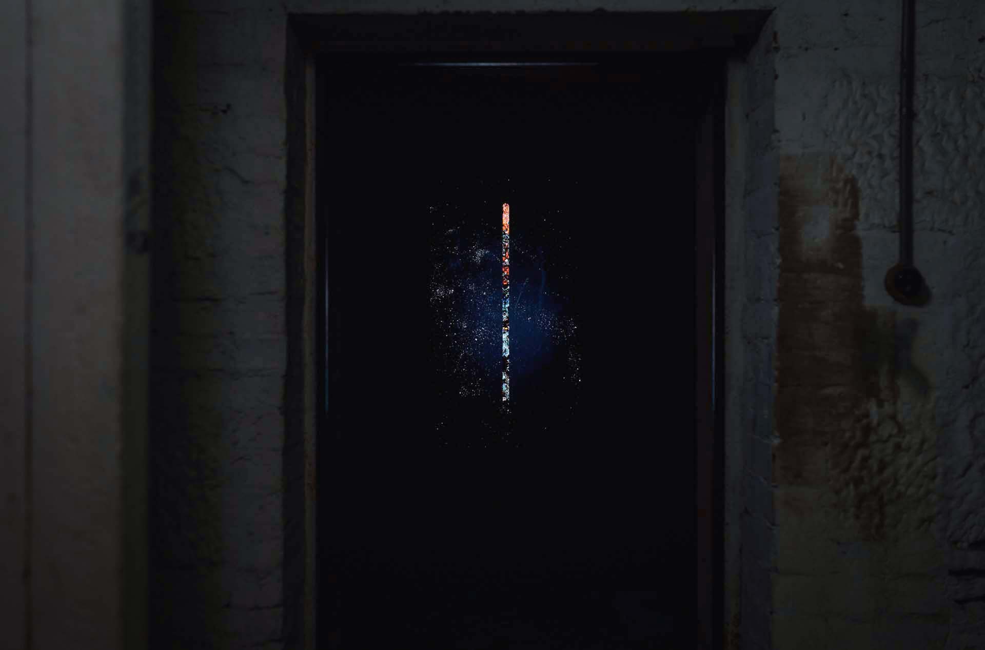 Illuminated vertical artwork installed within a stone doorway