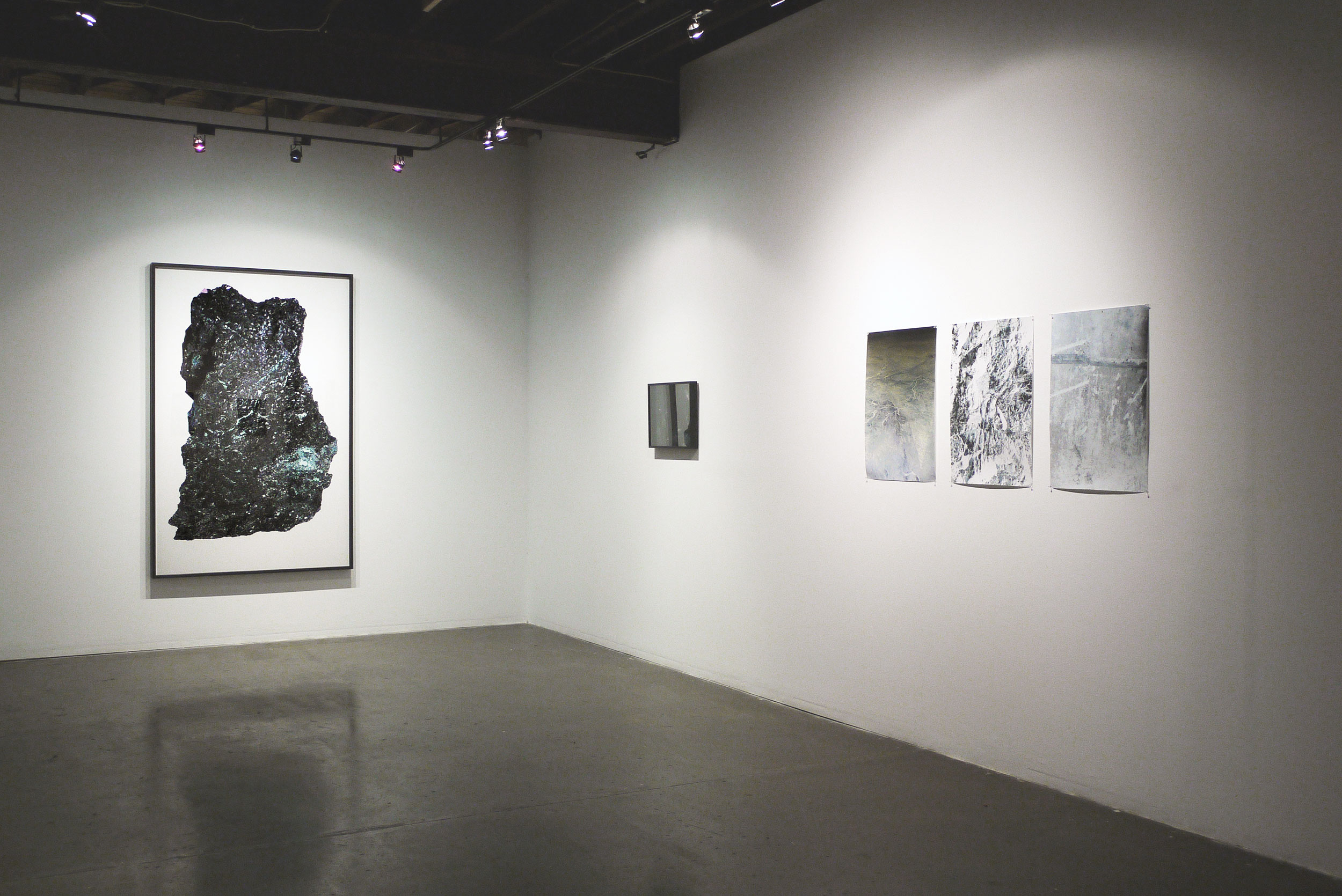 Gallery view with photographic works installed across two white walls