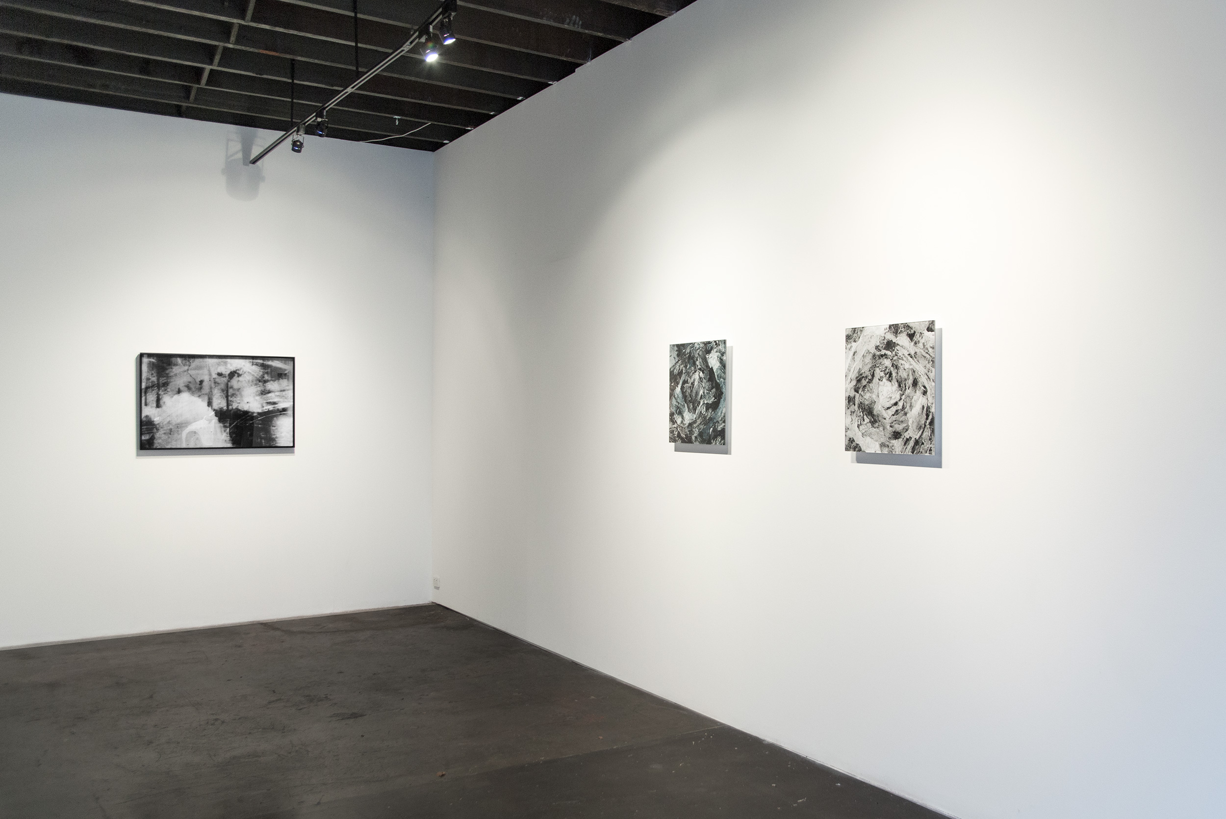 Gallery corner with four photographic works installed on white walls