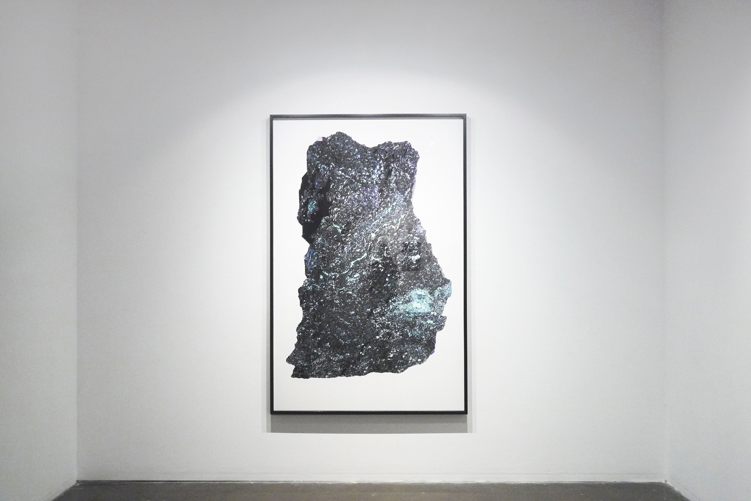 Large dark textured photographic artwork framed on a white gallery wall
