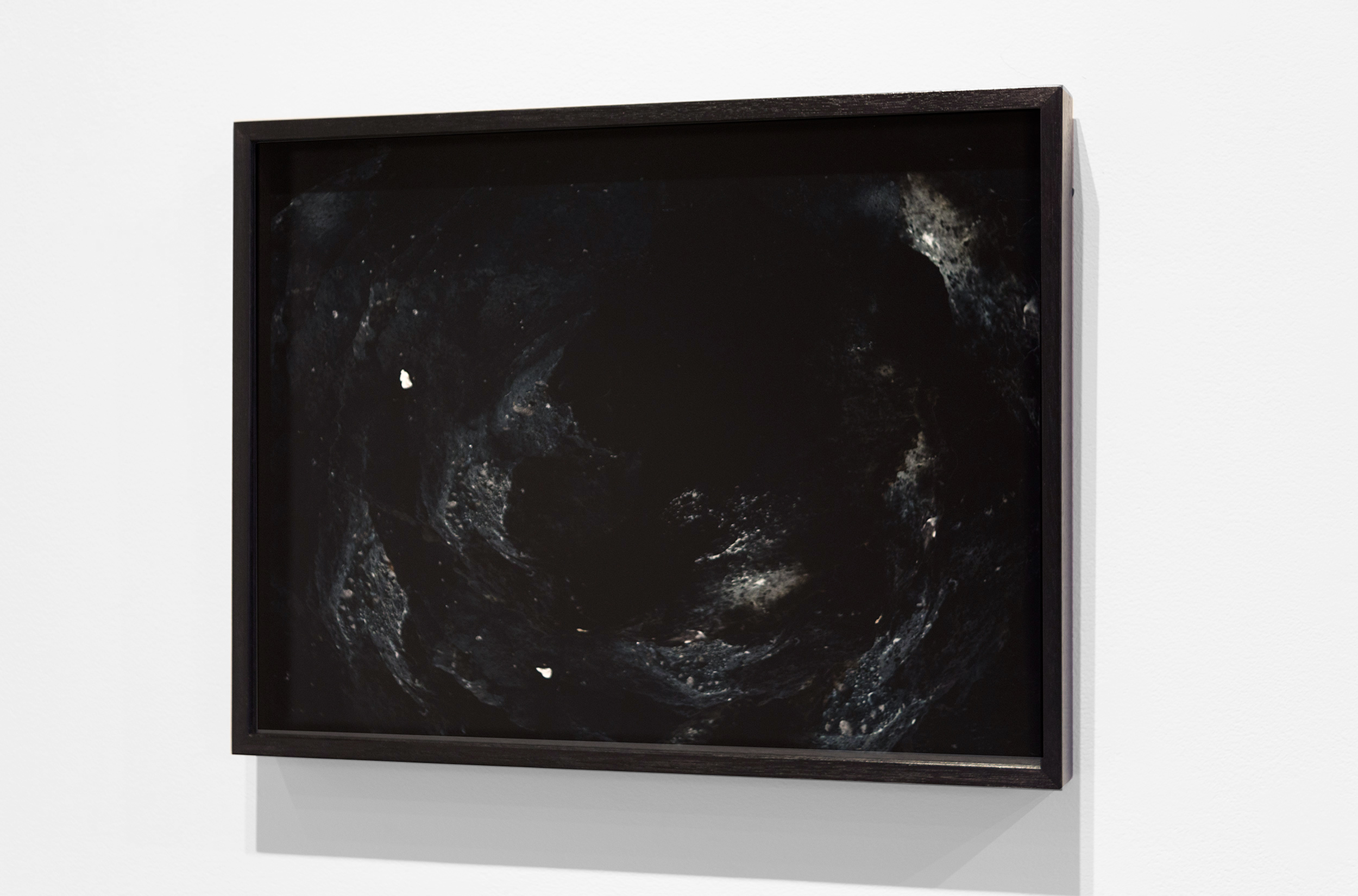 Dark circular abstract photographic work in a black frame