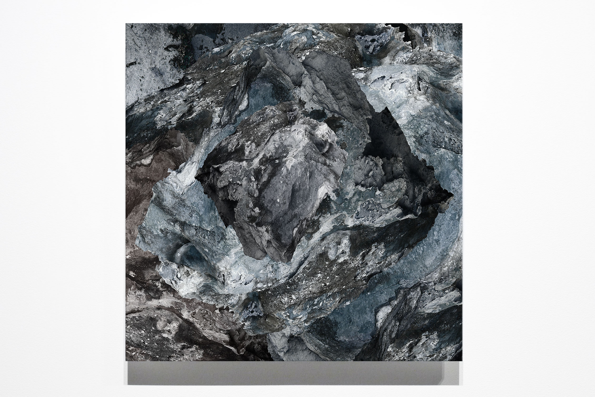 Square blue-grey artwork showing layered rock-like forms