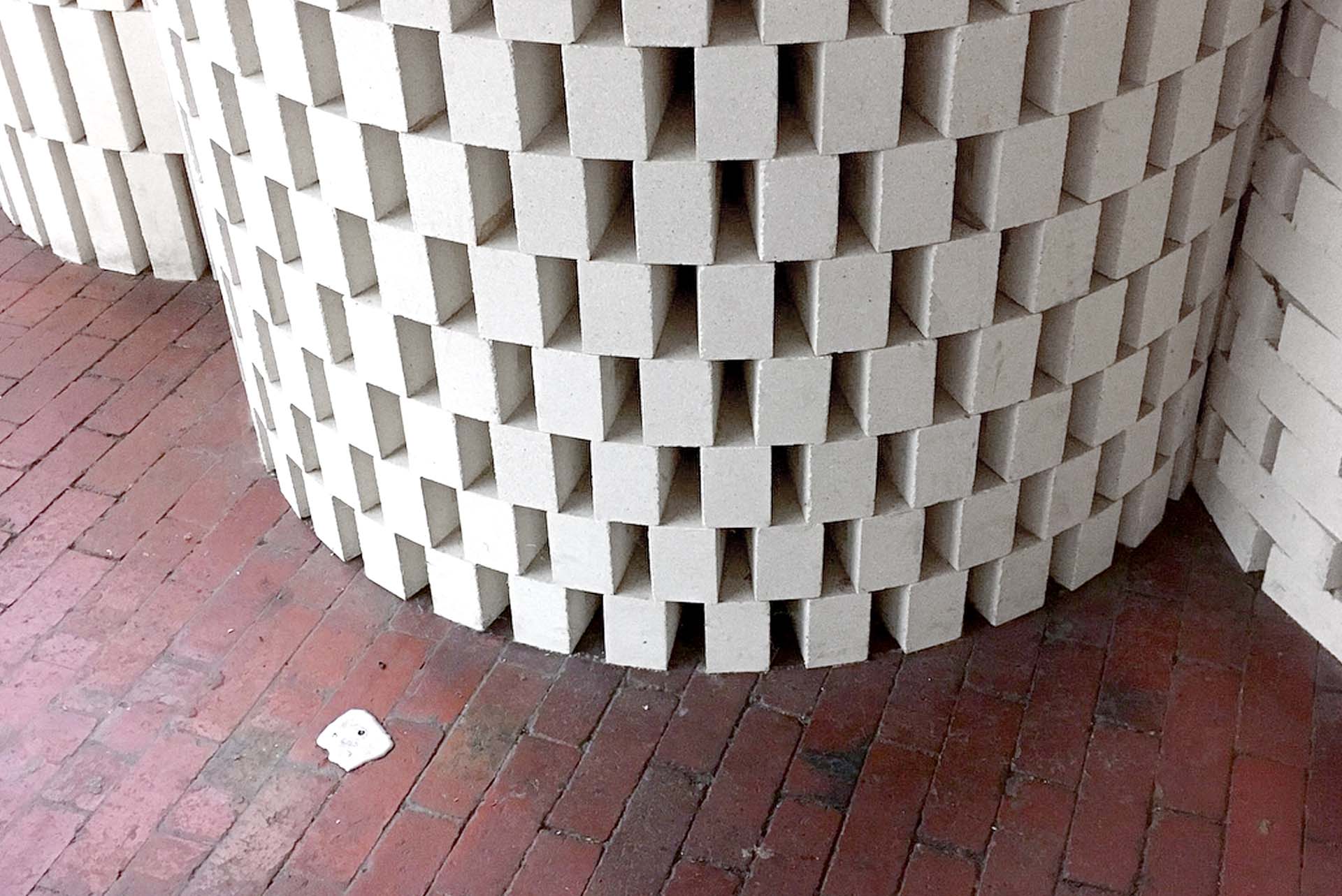 Pewter ingot embedded in a red brick floor beside a curved white brick wall