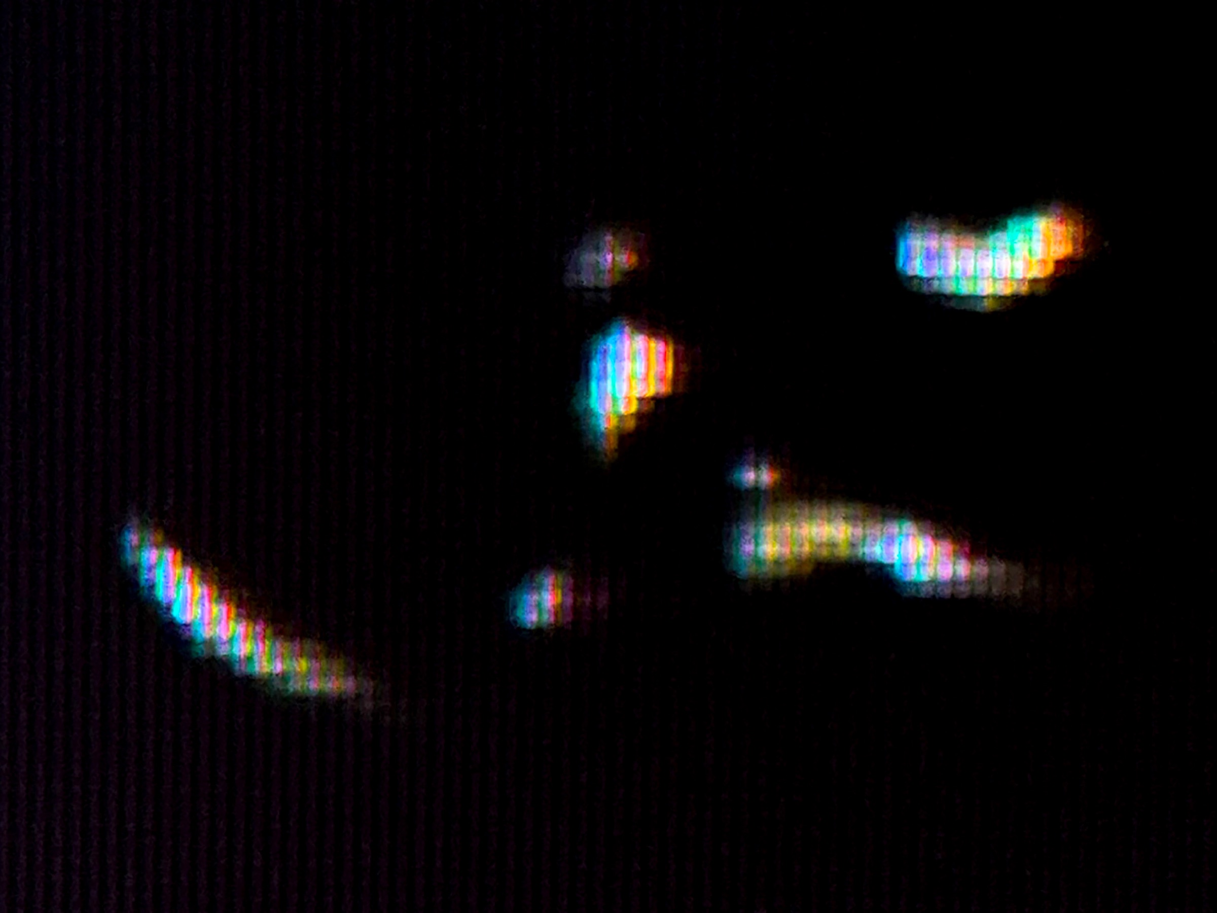 Small multicoloured light traces emerging from a dark field