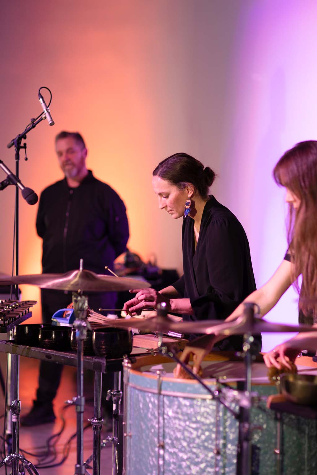 Kaylie Melville and Zela Papageorgiou performing with percussion instruments while Jon Butt stands behind them