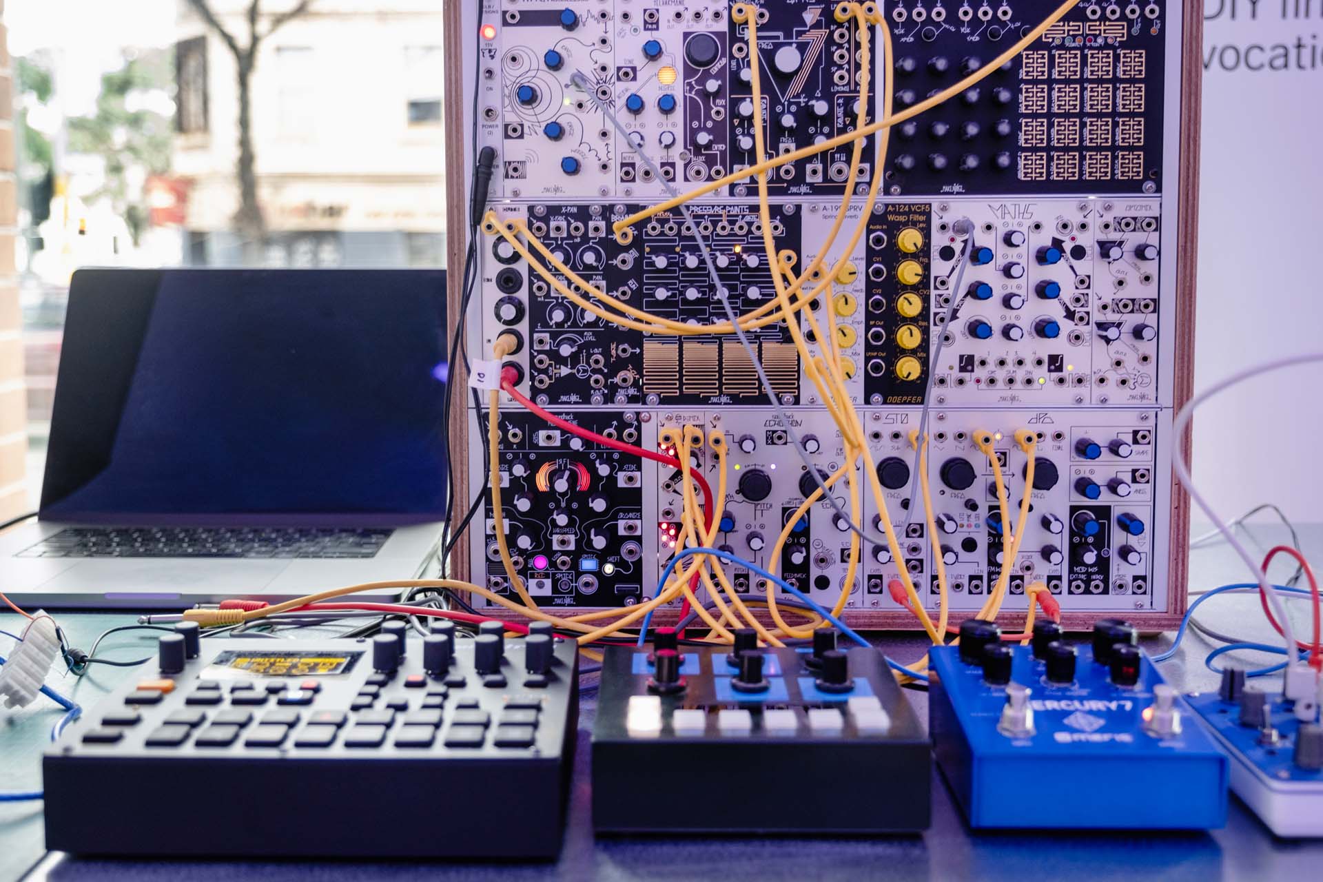 Modular synthesiser and sound equipment connected by coloured patch cables